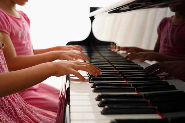 Deux enfants jouant à 4 mains sur un piano