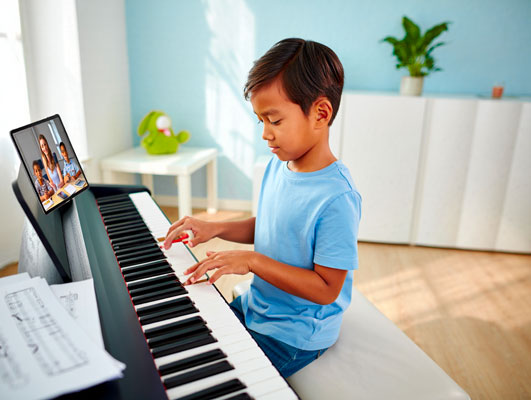 Enfant au piano pendant un cours collectif en ligne