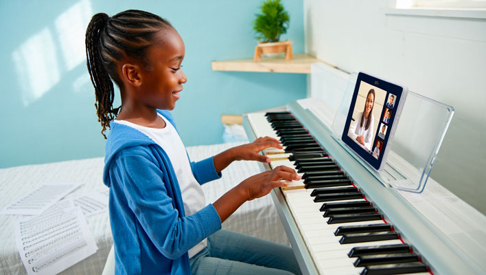 Enfant au piano pendant un cours collectif de piano en ligne